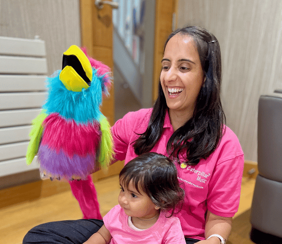 Smiling Teacher and Baby with colourful parrot puppet